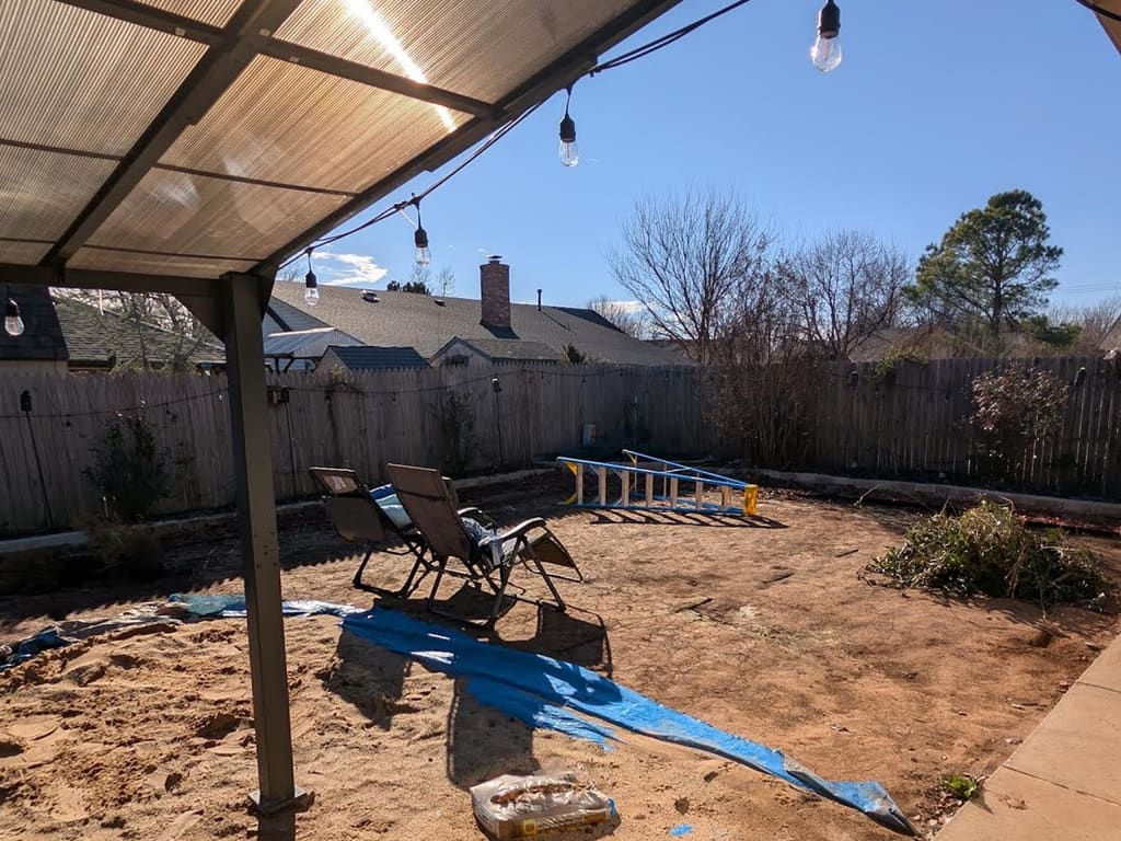 Before: bare dirt yard beside a paver patio under a covered pergola